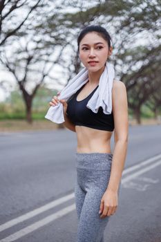 young sporty woman with white towel resting after workout sport exercises outdoors at the park