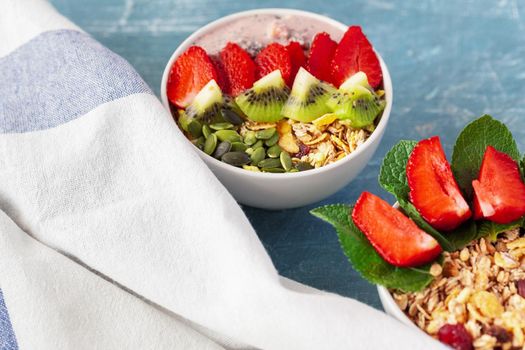 Bowl of homemade granola with yogurt and fresh berries on wooden background