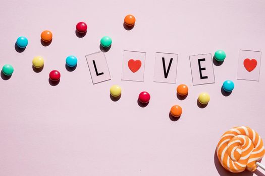 Pink candies, lollipops and jelly beans on white wooden background. Sweet greeting card. Copy space. Top view