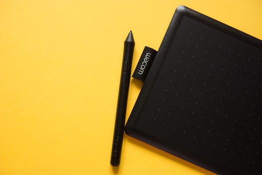 Tver, Russia - February 3, 2020; Top view of Wacom graphic tablet on yellow background. Space for text. Selective focus.