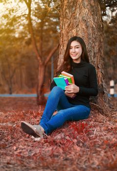 young woman holding a book in the park