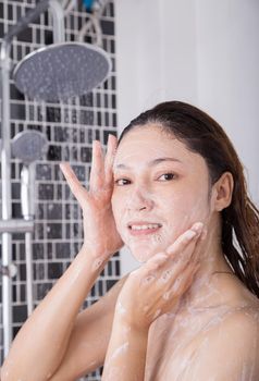 woman washing face in shower foaming in the bathroom