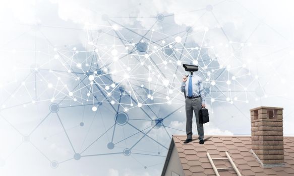 Faceless businessman with camera zoom instead of head standing on house roof