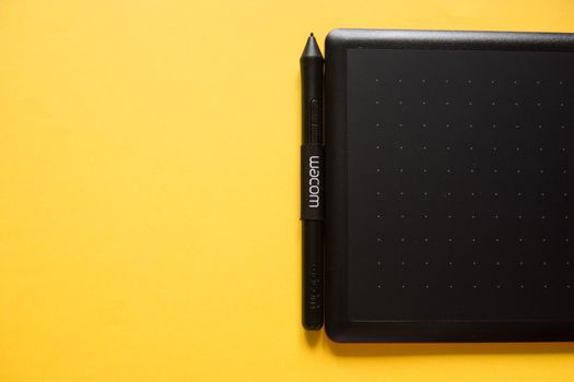 Tver, Russia - February 3, 2020; Top view of Wacom graphic tablet on yellow background. Space for text. Selective focus.