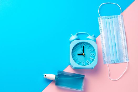 Medical face mask on pink and blue paper background with copy space top view