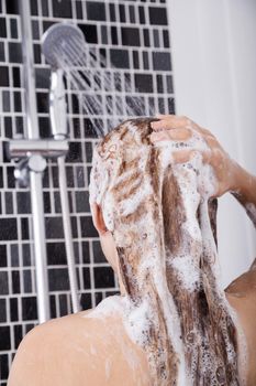 woman washing her head and hair in the shower by shampoo, rear view