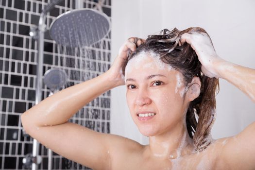 unhappy woman washing head with shampoo and the shower