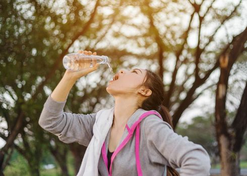 young sporty woman drinking water in the park