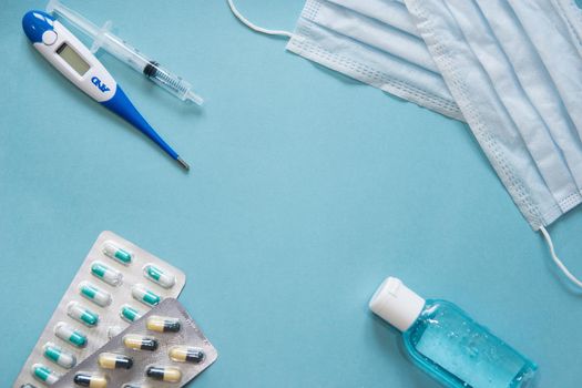 Virus prevention and treatment: wearing masks, hand disinfection, taking antiviral drugs and vitamins. First aid kit with medicines on a blue background.