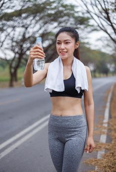 young sporty woman with bottle of water in the park
