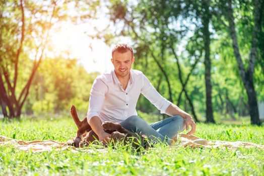 Young man hugs a dog. Spending time with friends in the park