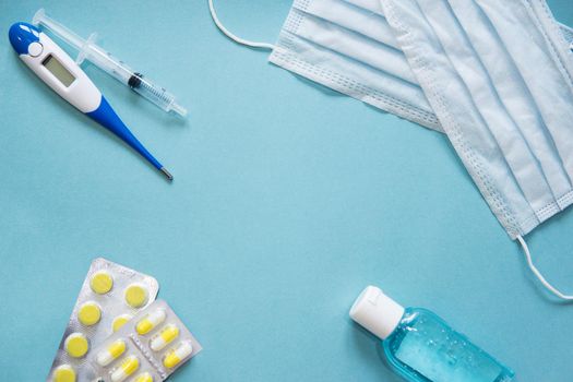 Virus prevention and treatment: wearing masks, hand disinfection, taking antiviral drugs and vitamins. First aid kit with medicines on a blue background.