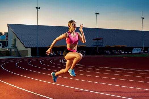 Runner sprinting towards success on run path running athletic track. Goal achievement concept. Female athlete sprinter doing a fast sprint for competition on red lane at an outdoor field stadium.