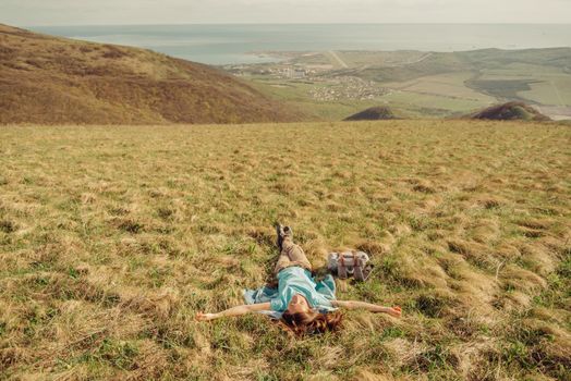 Happy hiker young woman lying on summer meadow in the mountains