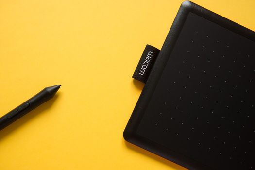 Tver, Russia - February 3, 2020 Top view of Wacom graphic tablet on yellow background. Space for text. Selective focus.