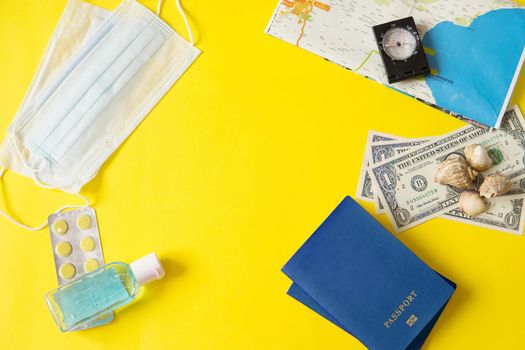 Travel concept with tablets, sterile mask, antiseptic and road symbols id passport, money, compass, map on yellow background. Stop traveling to dangerous places to prevent coronavirus. Space for text