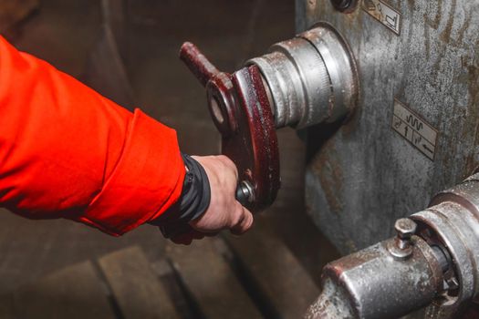 The hand of a working man in construction clothes holds the handle and controls the work of the milling machine in an industrial enterprise.