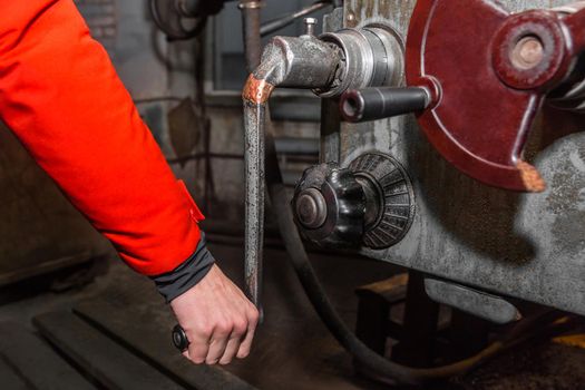 The hand of a man worker holds and controls the handle of a milling mill close-up in an industrial enterprise.