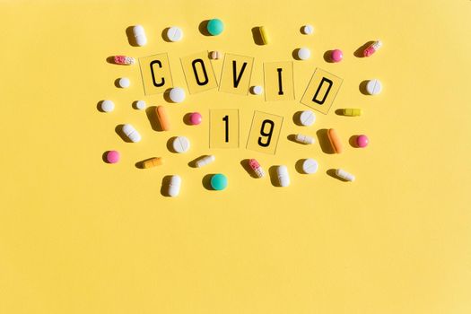 Wooden letters are lined with the word covid, pills with a medical mask. Concept on the theme of flu, virus.