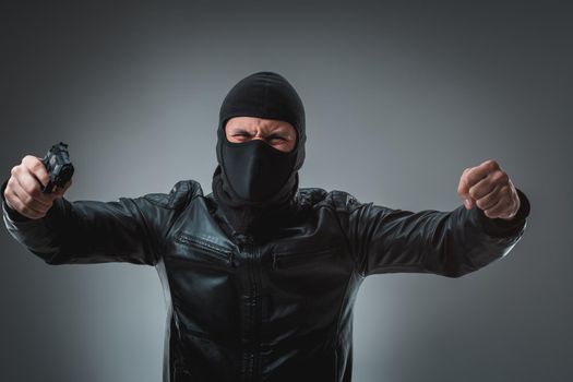 Robber in a mask with a gun, studio shot