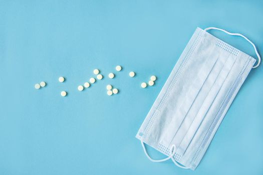 Respiratory mask and medicine in capsules on blue background.Virus prevention and treatment.