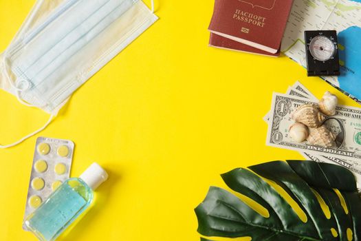 Travel concept with tablets, sterile mask, antiseptic and road symbols id passport, money, compass, map on yellow background. Stop traveling to dangerous places to prevent coronavirus. Space for text
