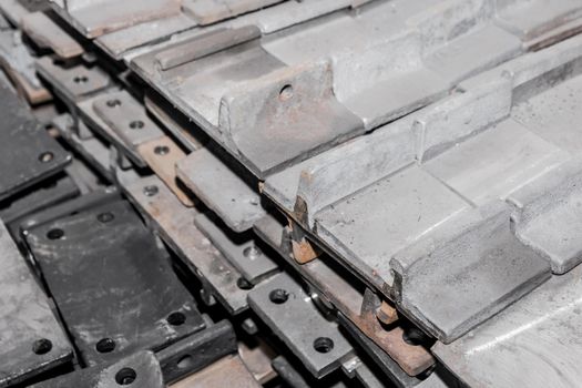 Iron parts of the workpiece for laying railway tracks metal structures in a heap at an industrial plant.