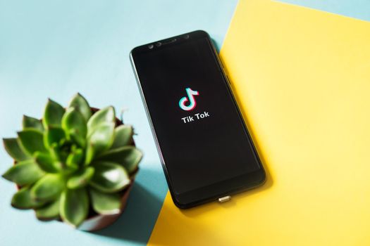 Tver, Russia - February 28, 2020 Tik tok logo on smartphone screen on blue and yellow background. Tik Tok icon. tik tok application. Tiktok Social media network.