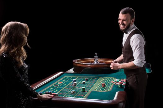 Croupier and woman player at a table in a casino. Picture of a classic casino roulette wheel. Gambling. Casino. Roulette. Poker