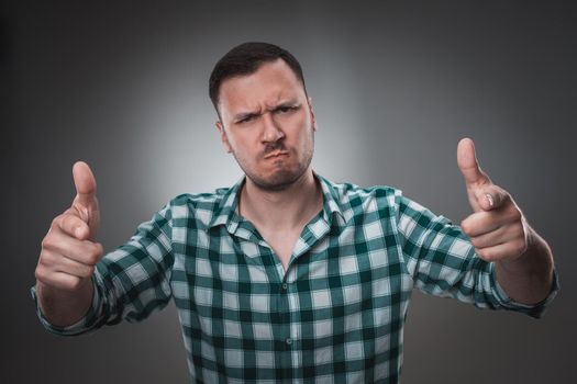 Portrait of excited man looking at the camera and points at you with a finger. Isolated on gray background. Emotion concept