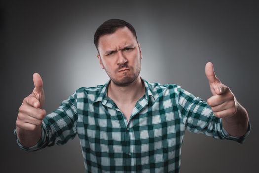 Portrait of excited man looking at the camera and points at you with a finger. Isolated on gray background. Emotion concept