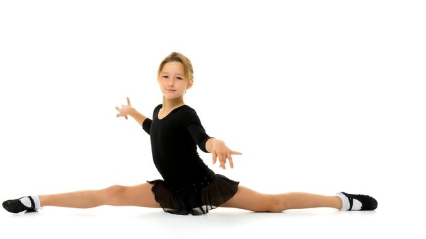 A little girl performs a gymnastic twine. The concept of fitness and sports. Isolated on white background.