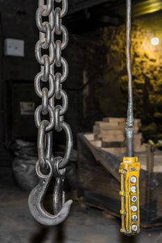 Remote control old control panel lifting industrial mechanism iron hook in the workshop of the industrial plant.