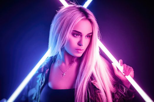 the beautiful stylish fashionable girl in bodysuit posing in photo Studio on dark background in neon light