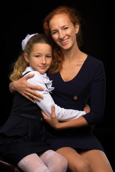 Happy family mom and little daughter, studio portrait.On black background