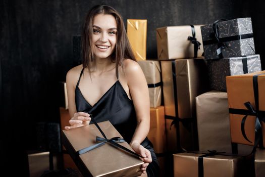 Young happy laughing woman in black dress with gift. High quality photo