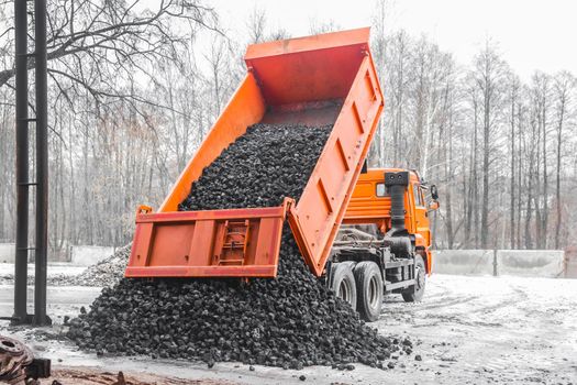 Dump truck in the industrial zone unloads coking coal from the body.