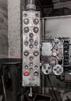 Old, dirty hanging vertical system and control panel with buttons for industrial equipment in the factory.