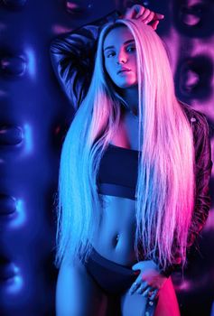 the beautiful stylish fashionable girl in bodysuit posing in photo Studio on dark background in neon light