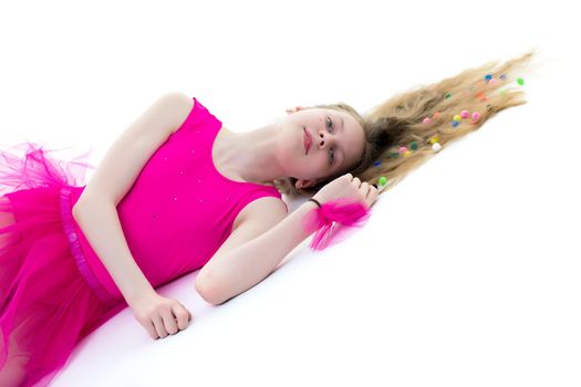 Beautiful girl gymnast schoolgirl lying on the floor with long hair spread out on the floor, in which multicolored confetti are braided. The concept of sport, style and fashion. Isolated on white background.