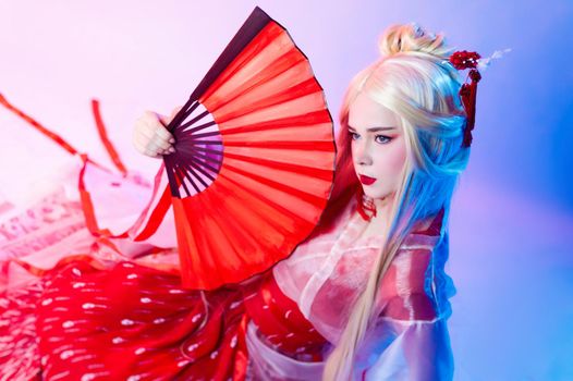 the woman in a geisha costume with fans sits on a white background