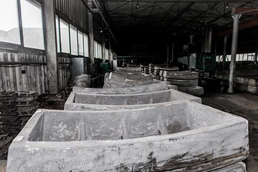 Cast iron tubing reinforced concrete cast products for lining distillation tunnels and underground structures are stored in the warehouse of the industrial plant.