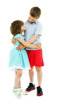 Charming little girl hugging a tall boy with blond hair. A romantic couple is happy with the joint time brought. A happy sister hugs her brother. The concept is a happy childhood. Isolated on white background.