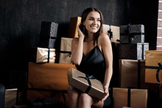 Young happy laughing woman in black dress with gift. High quality photo