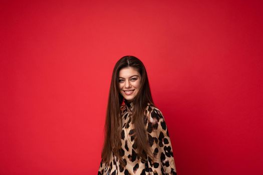 Photo of young happy smiling beautiful fashionable sexy brunette woman wearing stylish leopard blouse isolated on red background with empty space. Positive concept.