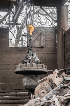 Magnetic scrap crane recycles and unloads junk and old metal in a landfill.