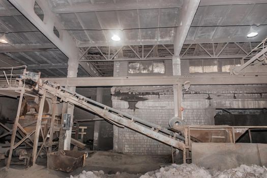 Old conveyor belt in the industrial workshop of the plant or enterprise for the processing of sand, soil and land factory.