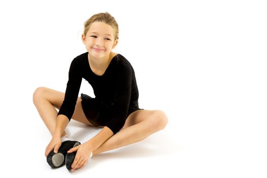 A sweet little gymnast girl performs an acrobatic element on the floor. The concept of sport, healthy lifestyle. Isolated on white background.