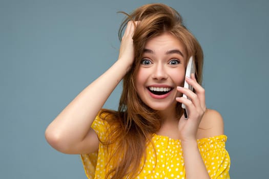 Closeup Photo of attractive crazy amazed surprised young woman wearing casual stylish clothes standing isolated over background with copy space holding and using mobile phone looking at camera.