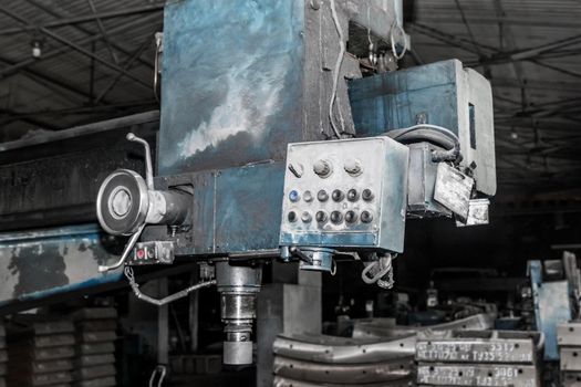 Old milling machine tool with control panel and buttons and equipment for metalworking in the workshop of an industrial plant.